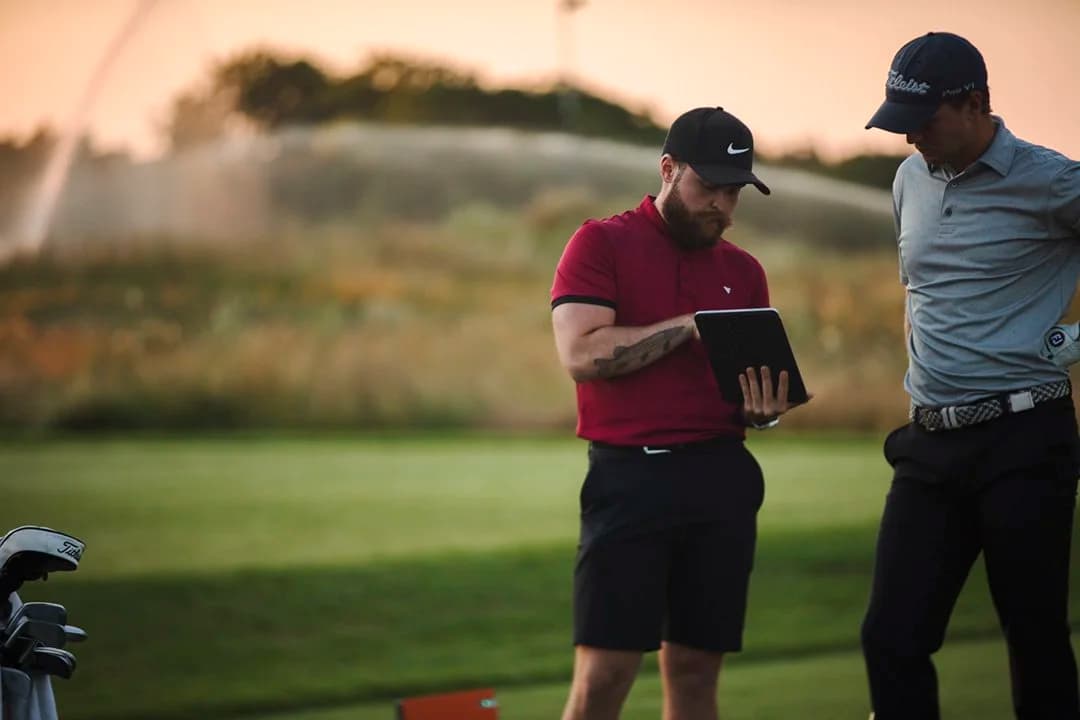 PGA coach reviewing swing data on iPad with student